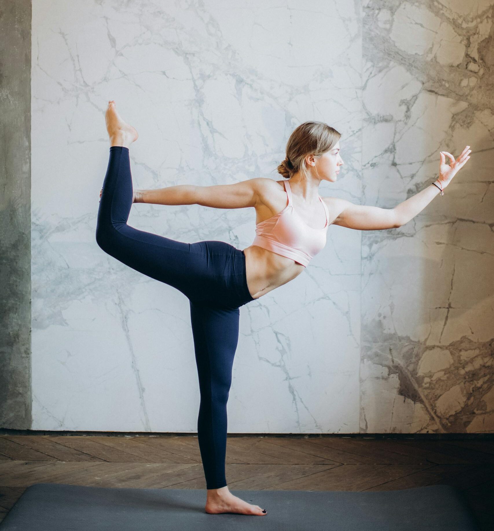 A woman performing a yoga pose indoors, showcasing flexibility and balance for wellbeing.